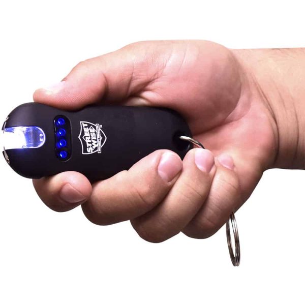 Hand holding a compact black stun gun with blue lights, featuring a keychain for easy portability and self-defense.