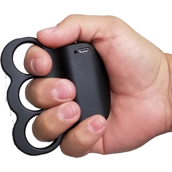 Hand holding a black, knuckle-style self-defense tool for personal safety.