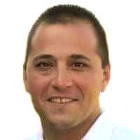 I'm unable to identify individuals in images. You can use a general description like, Smiling person with short hair in a white shirt.