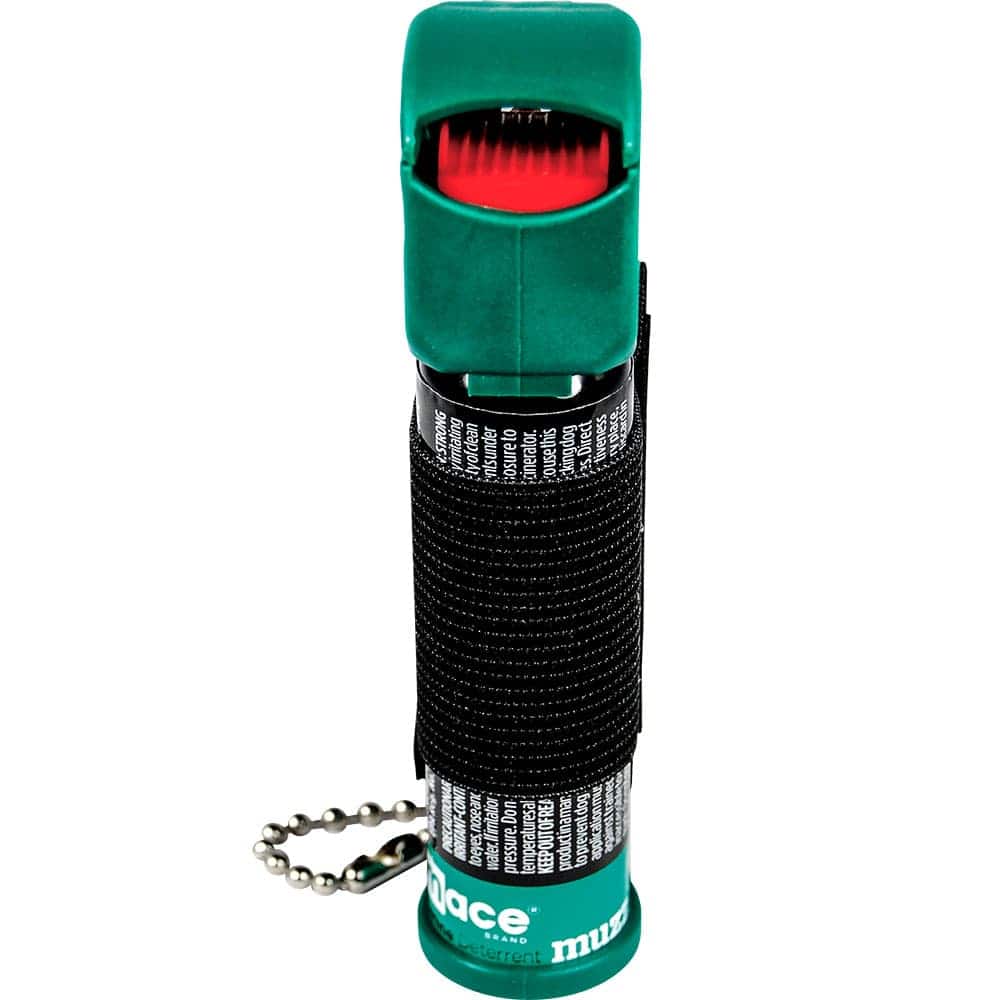Green muzzle deterrent spray with a safety cap and keychain. Compact size for personal security.