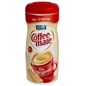 Coffee-Mate The Original creamer bottle, red lid, cholesterol and lactose-free, beside a cup of coffee and wafers.
