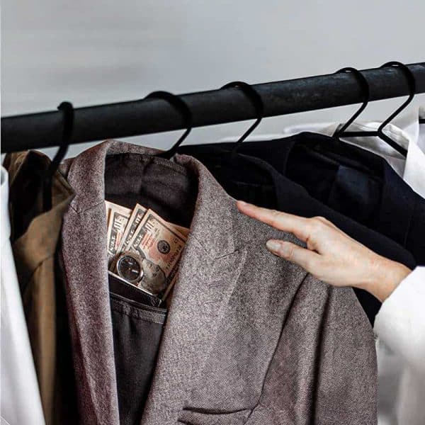Suit jacket on hanger with hidden cash and watch in pocket, emphasizing discreet storage and luxury fashion.