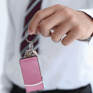 Hand holding car keys and a pink key fob, representing security and convenience in transportation.