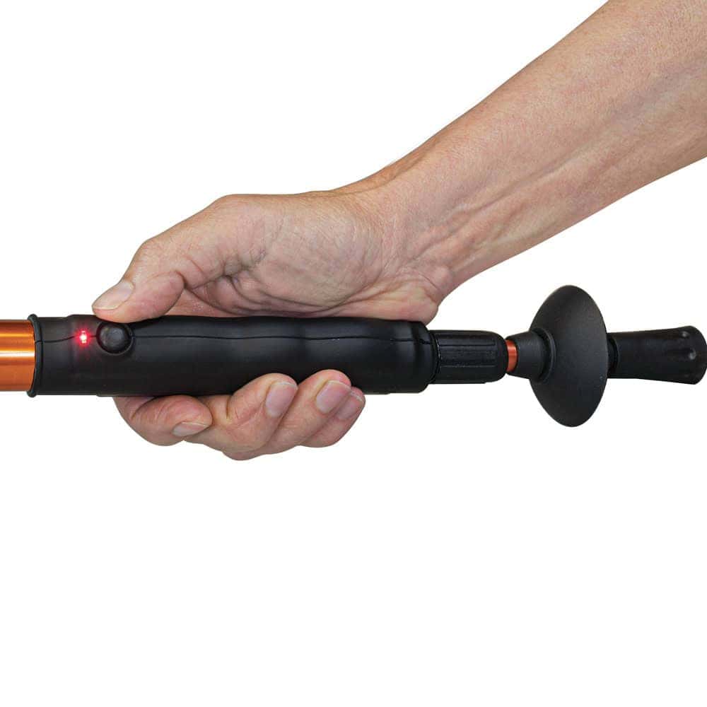 Hand holding a handheld tool with a red light indicator, featuring a black grip and control button.