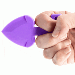 Hand squeezing a purple silicone heart-shaped stress toy.