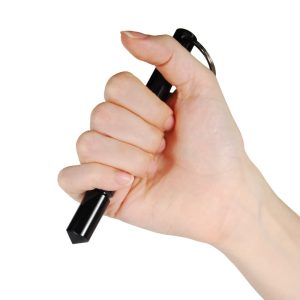 Hand holding a black self-defense kubotan keychain for personal safety.