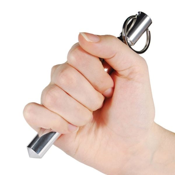 Hand holding a metal kubotan keychain for personal defense on a white background.