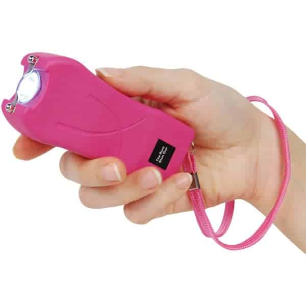Hand holding a pink stun gun with wrist strap, used for self-defense and personal safety.