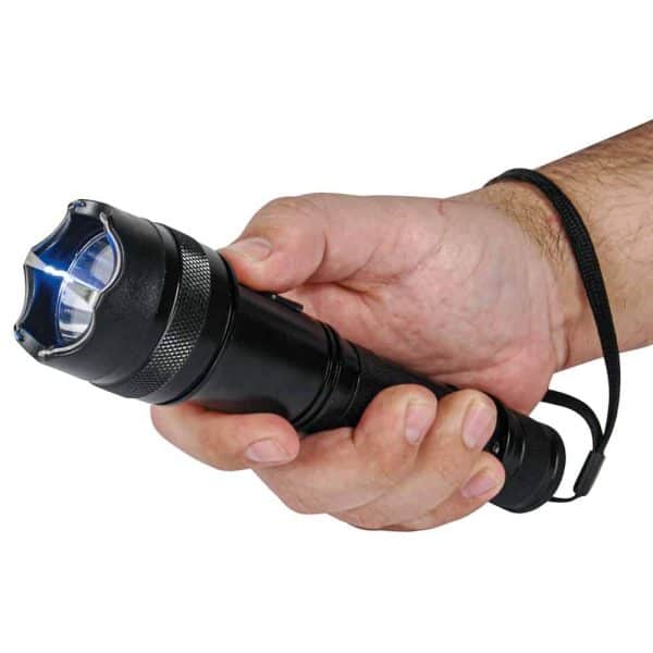 Hand holding a black flashlight with safety strap, emitting bright blue light.