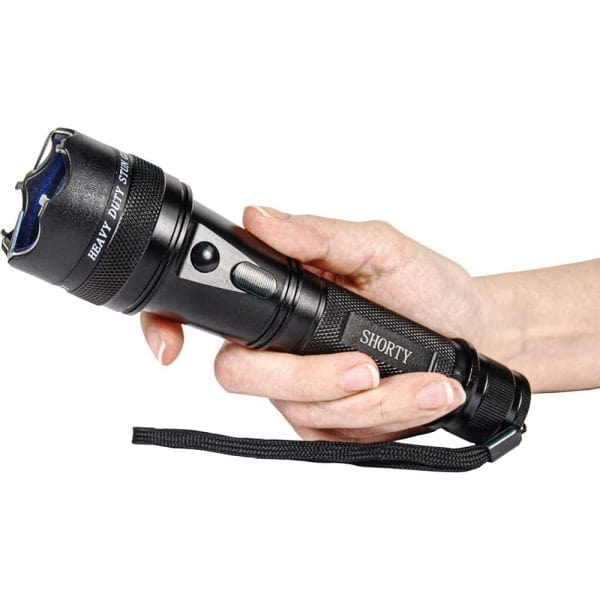 Person holding a black heavy-duty flashlight with tactical features and strap.