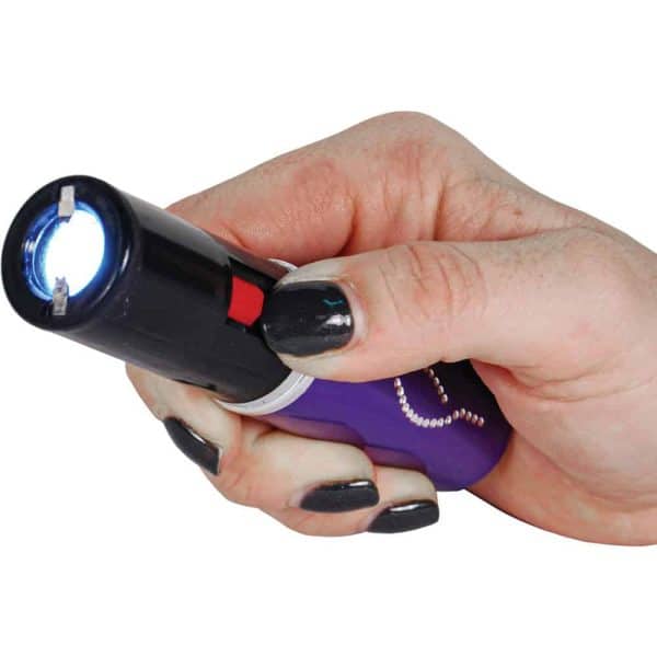 Hand holding a purple flashlight with painted nails, light is on.