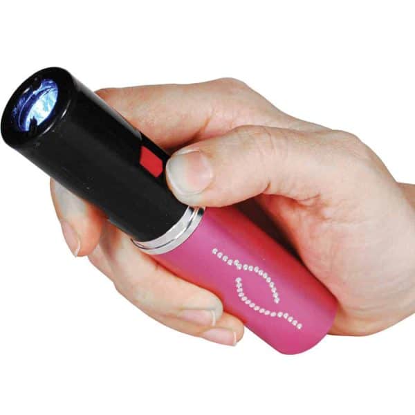 A hand holding a lipstick-shaped stun gun with a bright light activated for self-defense.