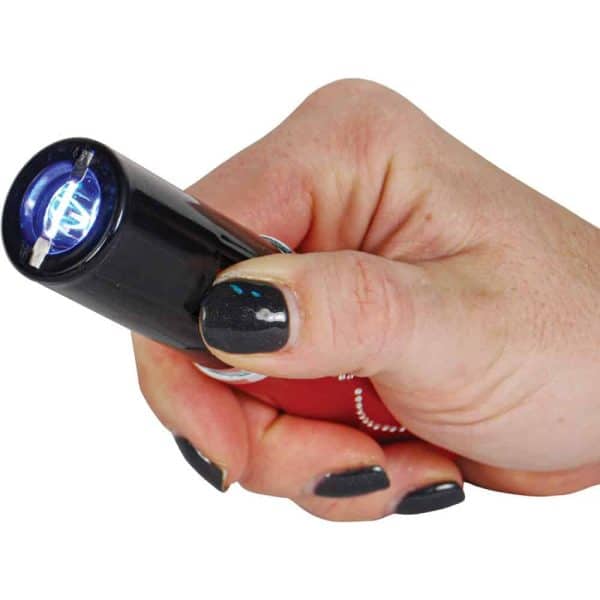 Close-up of a hand holding a small LED flashlight, illuminating with a bright blue light.