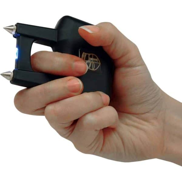 Hand holding a black stun gun with blue spark, white background for safety and self-defense concept.
