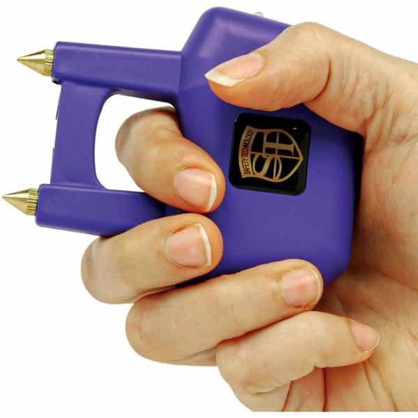 Close-up of a hand holding a purple personal safety tool with dual metal spikes for self-defense.