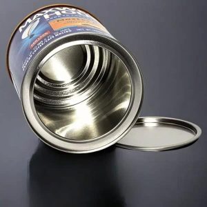 Open empty tin can with lid on dark reflective surface.