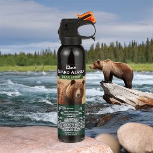 Mace Guard Alaska bear spray can with background of forest and stream with a bear on a rock.