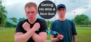 Two men in a park with a stun gun, one with crossed arms, and text Getting Hit With A Stun Gun above.