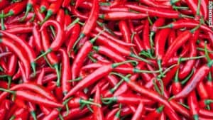 A vibrant pile of fresh red chili peppers with green stems, perfect for adding a spicy kick to any dish.