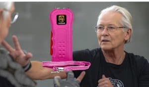 Elderly person holding a pink self-defense taser, focusing on personal safety and empowerment.