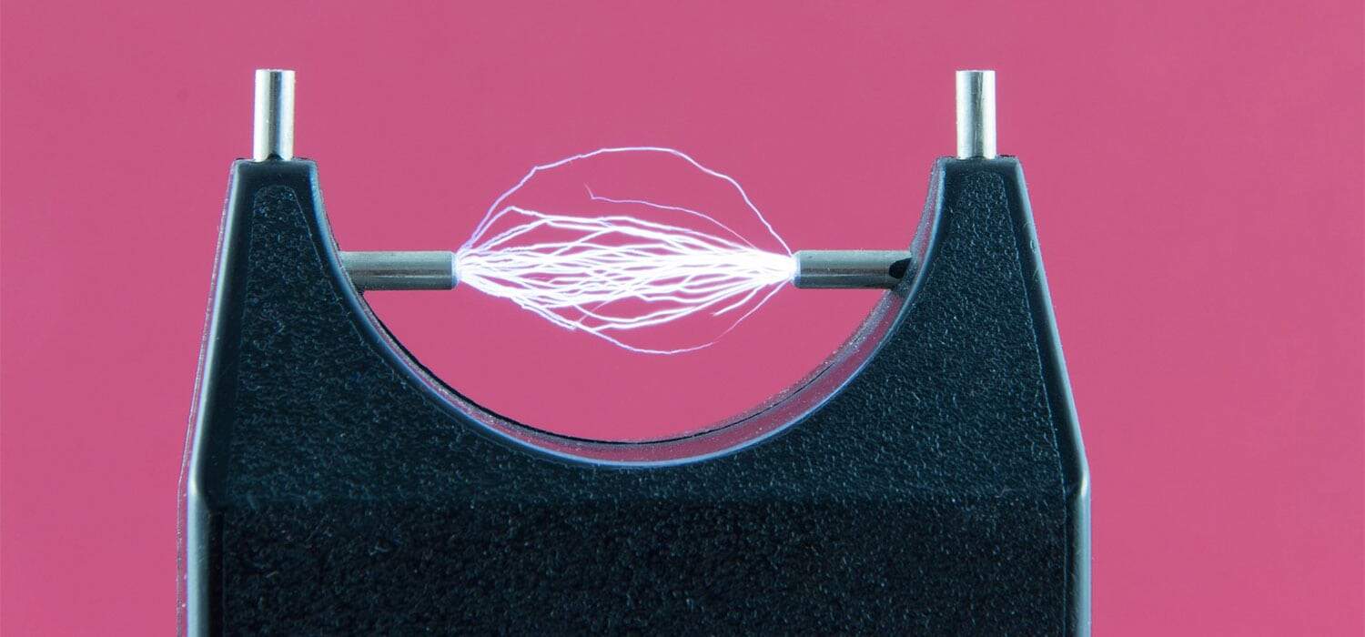 Electric current between two electrodes against pink background.