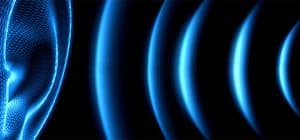 Digital ear with blue sound waves representing technology and audio frequency on a dark background.