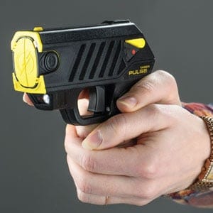 Hand holding a Taser Pulse stun gun, designed for self-defense with yellow accents against a gray background.